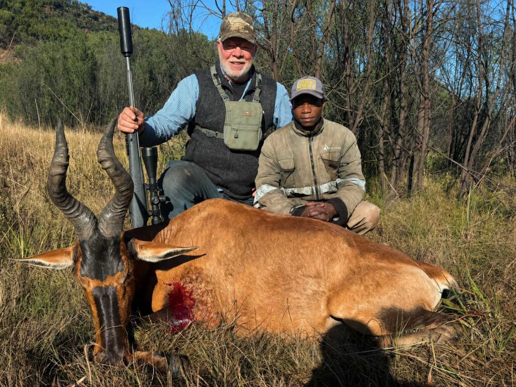 Hunter and professional guide posing with a trophy antelope after a successful African hunting safari.