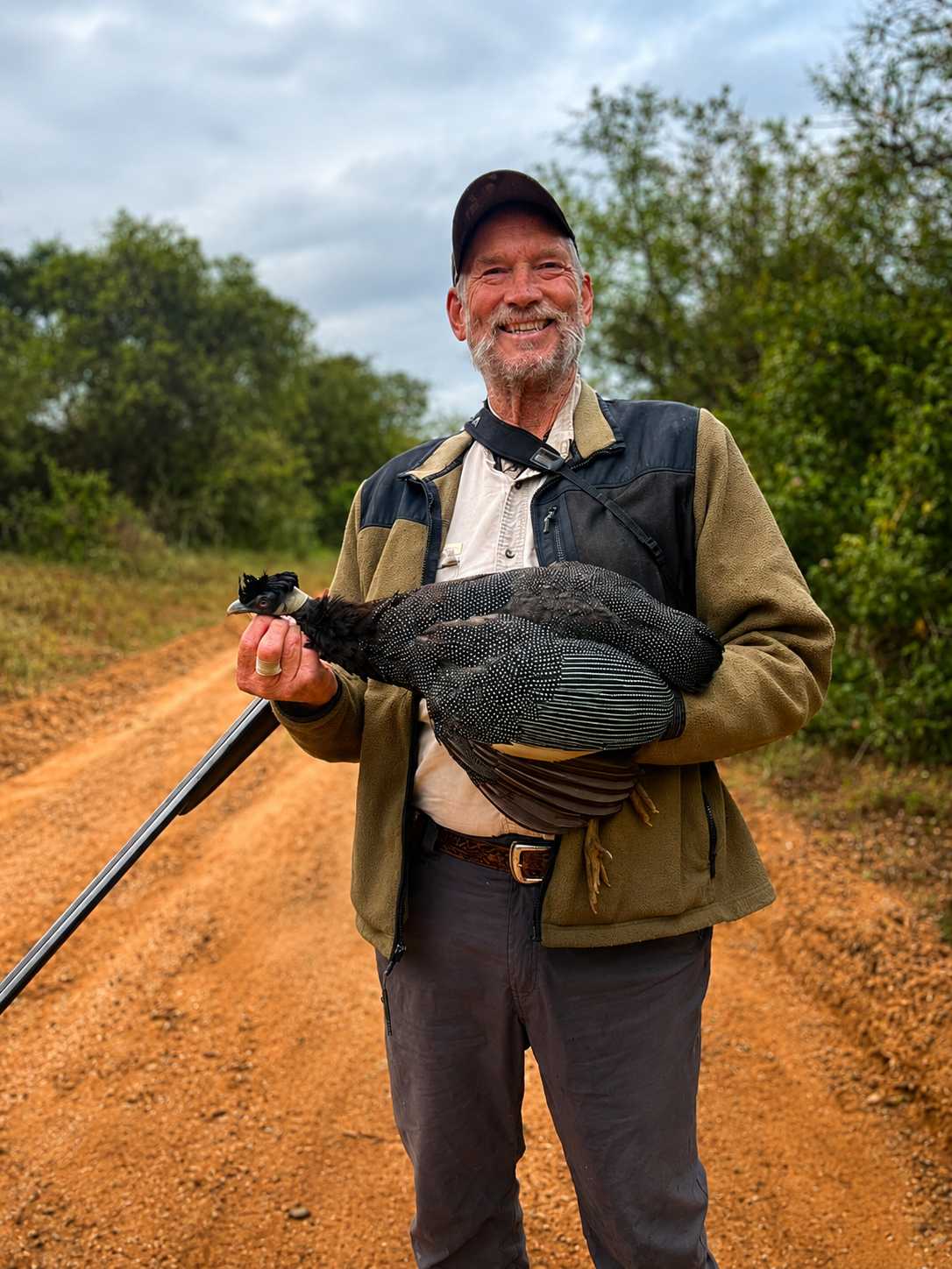 Hunter holding a helmeted guineafowl after a bird hunting safari in South Africa.