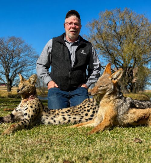 Hunter posing with a serval and jackal during an African hunting safari