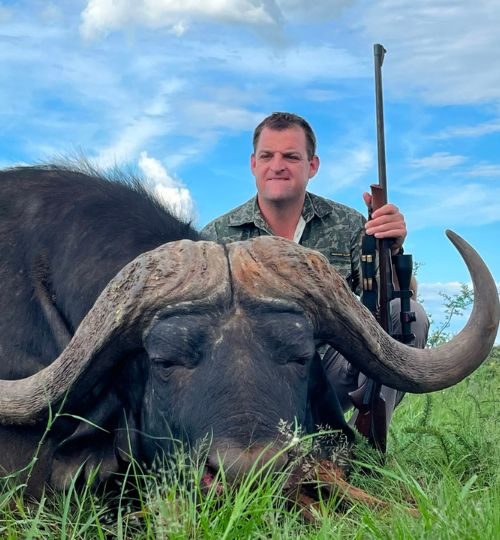 Hunter posing behind a trophy Cape buffalo during a South African hunting safari